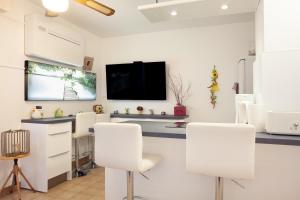 Habitación con sillas blancas y TV de pantalla plana. en Studio proche des plages, en Le Pradet