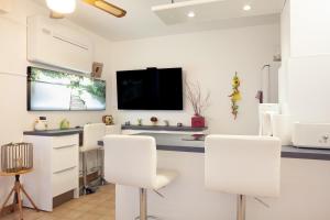a room with white chairs and a flat screen tv at Studio proche des plages in Le Pradet