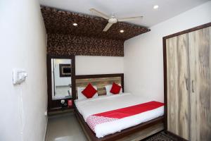 Schlafzimmer mit einem Bett mit roten Kissen und einem Spiegel in der Unterkunft Super OYO Flagship 4957 Hotel China Town in Bhairaun Ghāt