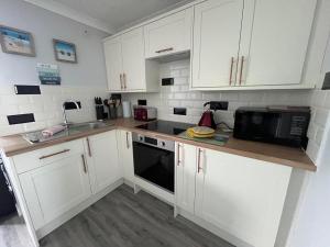 a kitchen with white cabinets and a black microwave at 246, Belle Aire, Hemsby - Beautifully presented two bed chalet, sleeps 5, pet friendly, close to beach! in Great Yarmouth
