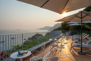a balcony with chairs and tables and an umbrella at Il Barilotto in Positano