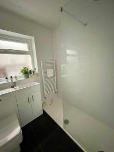 a white bathroom with a sink and a shower at The Ridge Bungalow, at the highest point in the Heart of Cheshire in Frodsham