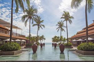 - une piscine dans un complexe avec des palmiers et l'océan dans l'établissement Resort Villa Da Nang Luxurious Abogo, à Đà Nẵng