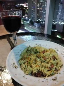 a plate of pasta on a table with a glass of wine at Loft Completo próx. GRU airport in Guarulhos