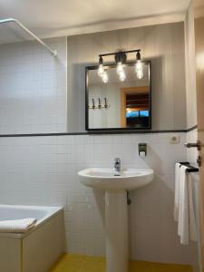 e bagno con lavandino, specchio e vasca. di Apartamentos Ciudad Santiago a Santiago de Compostela