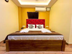 a bedroom with a large bed with a red headboard at Hotel MTown in Port Blair