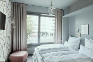 1 Schlafzimmer mit 2 Betten und einem großen Fenster in der Unterkunft NOMADS by Suite030 high class apartments, 1-2 bedrooms in Berlin
