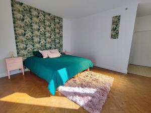1 dormitorio con 1 cama con manta verde y alfombra en Villa Loha Maison de vacances, en Saint-Gaudens