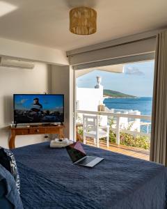 um quarto com uma televisão e uma cama com um computador portátil em Loft Grécia In em Arraial do Cabo