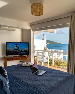 a bedroom with a television and a bed with a laptop at Loft Grécia In in Arraial do Cabo
