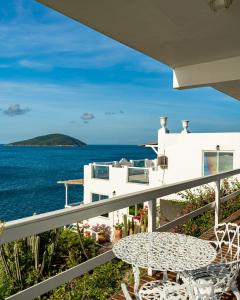 a balcony with a table and a view of the ocean at Loft Grécia In in Arraial do Cabo