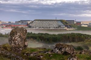 a large building in the middle of a river with fog at Hilton Garden Inn Faroe Islands in Tórshavn