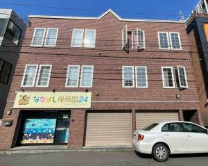 un coche blanco estacionado frente a un edificio de ladrillo en 中島公園徒歩3分、Susukino（薄野）内、格安有料駐車場あり(205号室） en Sapporo