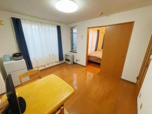 1 dormitorio y sala de estar con mesa de madera. en 中島公園徒歩3分、Susukino（薄野）内、格安有料駐車場あり(205号室） en Sapporo