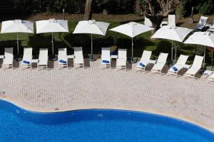 eine Gruppe von Stühlen und Sonnenschirmen neben einem Pool in der Unterkunft Hotel Pabisa Chico in Playa de Palma