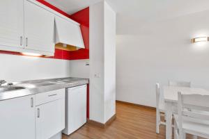 a kitchen with white cabinets and a table and chairs at Apartamentos Pabisa Orlando in Playa de Palma