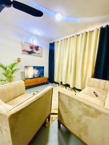 a living room with two couches and a flat screen tv at Drew Apartment Tanga in Tanga