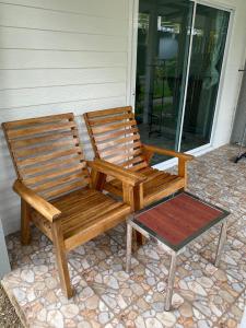 2 sillas de madera sentadas en un porche junto a un taburete en Smile Resort Koh Mook, en Ko Mook