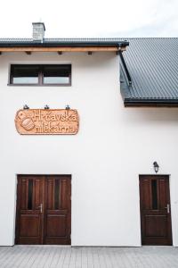 a sign on the side of a white building with two doors at Hrčavská Mlékárna in Bukovec