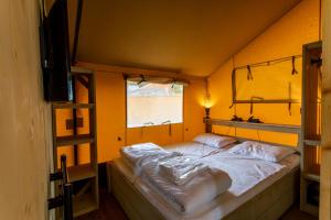 Cama en habitación con pared amarilla en Camping Vossenberg - op de Veluwe!, en Epe
