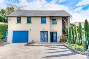 une maison avec des portes de garage bleues et des arbres dans l'établissement Gîte du Thouet - Appt avec piscine partagée, à Montreuil-Bellay