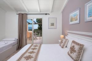 a white bedroom with a bed and a balcony at VOI Colonna Village in Golfo Aranci