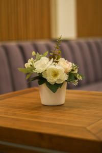 a white vase filled with flowers on a table at Merak Rooms & Caffe Bar in Šabac