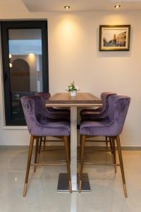 a dining room table with purple chairs in a room at Merak Rooms & Caffe Bar in Šabac