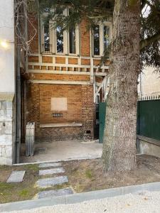 ein Backsteingebäude mit einer Bank neben einem Baum in der Unterkunft Bel appartement neuf et facile d'accès in Orléans