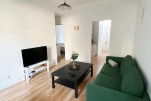 ein Wohnzimmer mit einer grünen Couch und einem Tisch in der Unterkunft Bel appartement neuf et facile d'accès in Orléans