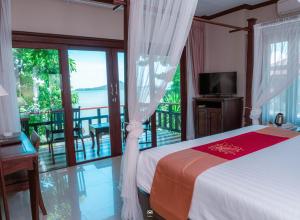 a bedroom with a bed and a balcony with a television at Victoria Cliff Hotel & Resort, Kawthaung in Kawthaung