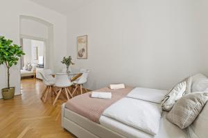 een witte slaapkamer met een bed en een eetkamer bij Cozy Vienna Apartments - 4 Min U6 Josefstädterstraße in Wenen