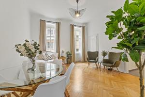 een woonkamer met een glazen tafel en witte stoelen bij Cozy Vienna Apartments - 4 Min U6 Josefstädterstraße in Wenen