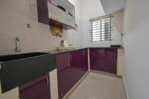 a kitchen with purple cabinets and a sink at HomeSlice Manzil - 1BHK in HSR in Bangalore