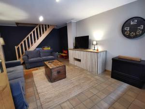 ein Wohnzimmer mit einem Sofa und einem TV in der Unterkunft Le petit Chermont in Saint-Hubert