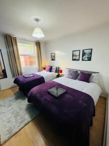 two beds in a bedroom with purple sheets at 2 Bedrooms House near Central London in London