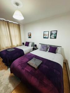 two beds in a room with purple sheets at 2 Bedrooms House near Central London in London