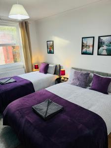 a bedroom with two beds with purple sheets at 2 Bedrooms House near Central London in London