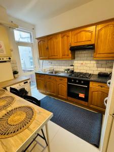 a kitchen with wooden cabinets and a table and a stove at 2 Bedrooms House near Central London in London