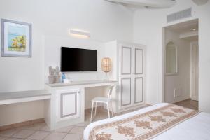 a white bedroom with a desk and a tv on a wall at VOI Colonna Village in Golfo Aranci