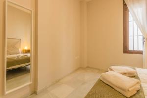 - une chambre avec un miroir, un lit et une fenêtre dans l'établissement APARTAMENTOS LOS ABUELOS - Cordoba, à Cordoue