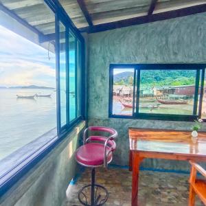 a room with a red chair and a table and windows at Poohry Seaview in Ko Lanta