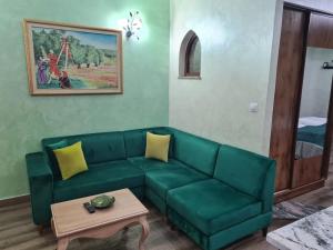 a living room with a green couch and a table at Mahdia - Baghdadi - Laourient Apartments, restaurant, café in Mahdia