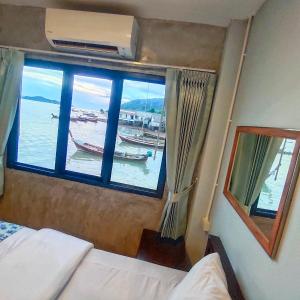 a bedroom with a window with a boat in the water at Poohry Seaview in Ko Lanta