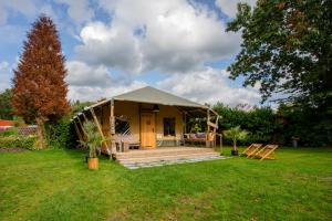 een klein huis in een tuin met een groen gazon bij Camping Vossenberg - op de Veluwe! in Epe