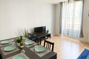 a dining room with a table and chairs and a television at Appartement 4 chambres spacieux et lumineux in Orléans