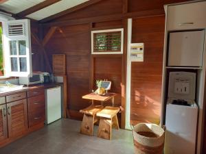 a kitchen with wooden walls and a table and a refrigerator at Ti Chalet à Malendure Bouillante in Bouillante
