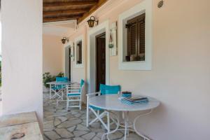 d'une terrasse avec une table blanche et des chaises bleues. dans l'établissement Villa Areti, à Astrakeri