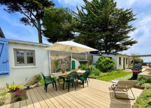 een houten terras met een tafel en stoelen en een parasol bij Face Mer Villa Le Petit Breton in Pornichet