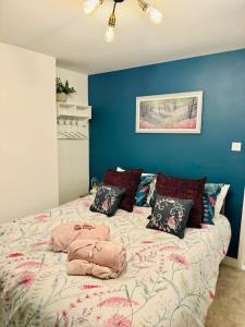a bedroom with a bed with pillows and a blue wall at Vine Cottage- Stunning newly renovated cottage 